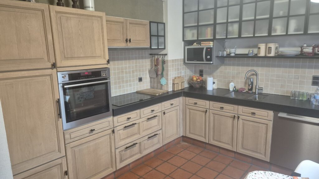 Moderne landelijke keuken met houten kasten, zwarte aanrechtblad en ingebouwde oven en magnetron